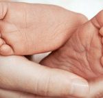 Feet of newborn baby on mother’s palm