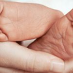 Feet of newborn baby on mother’s palm